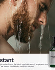 Ein bärtiger Mann steht unter fließendem Wasser während unten rechts die Bergamond and Birch Hand and Body Wash Grapefruit Flasche eingeblendet ist und der Eindruck einer erfrischenden reinigenden Dusche vermittelt wird.