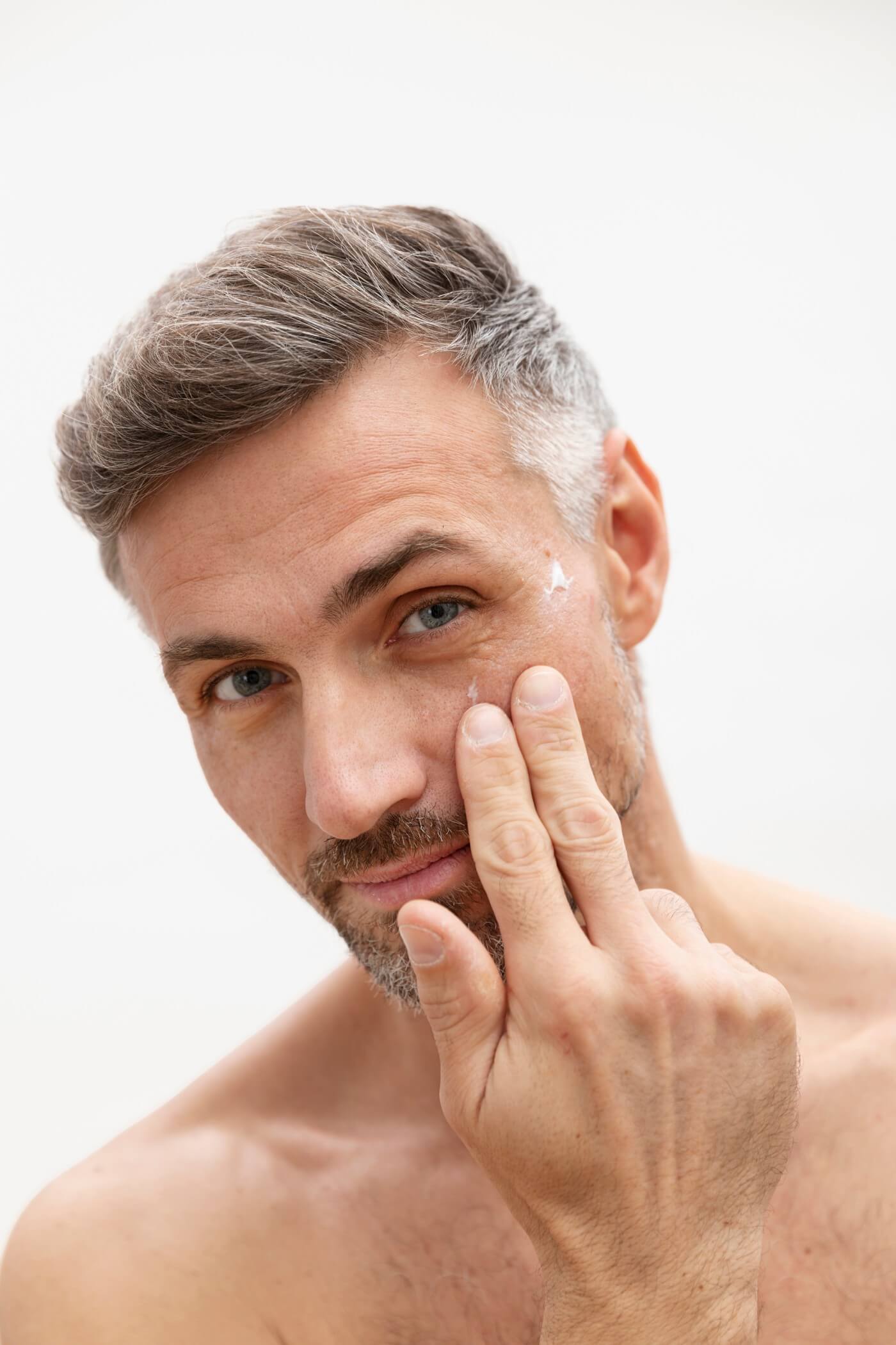Close-up of man applying anti-wrinkle cream around eyes – part of Bergamond & Birch's targeted skincare designed for firmness and hydration.